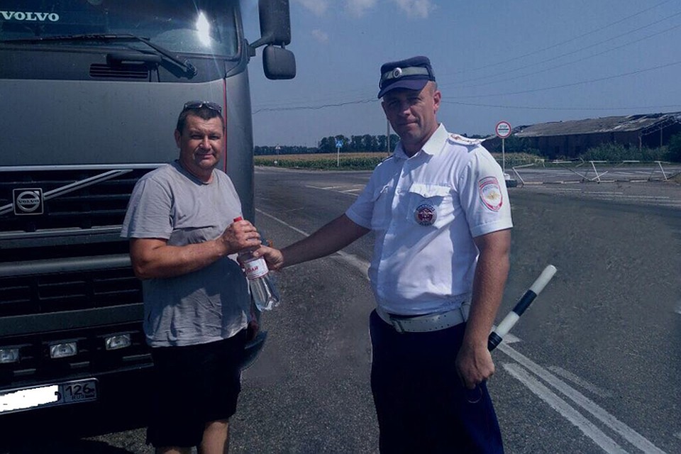 Сотрудник ГАИ не только дарит бытылочку воды, но и просит быть водителя внимательнее на дорогах. Фото: ГИБДД Краснодарского края.