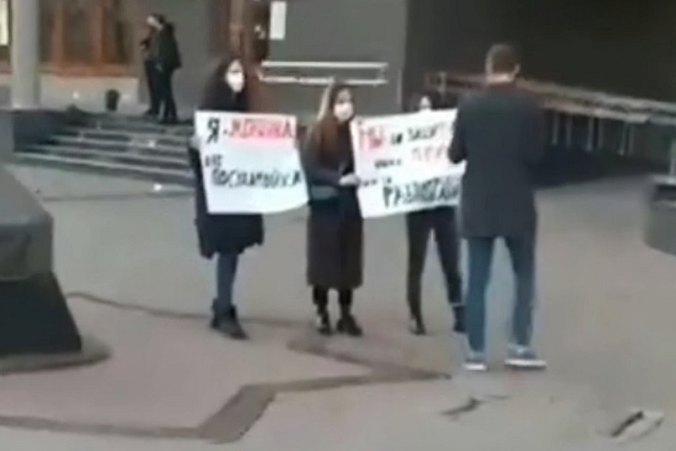 Девушки с плакатами зачем-то скрывали свои лица за медицинскими масками.